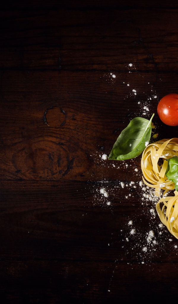 Паста с помидорами и листьями базилика на столе