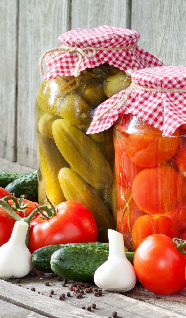Соленья из огурцов и помидоров с овощами на столе