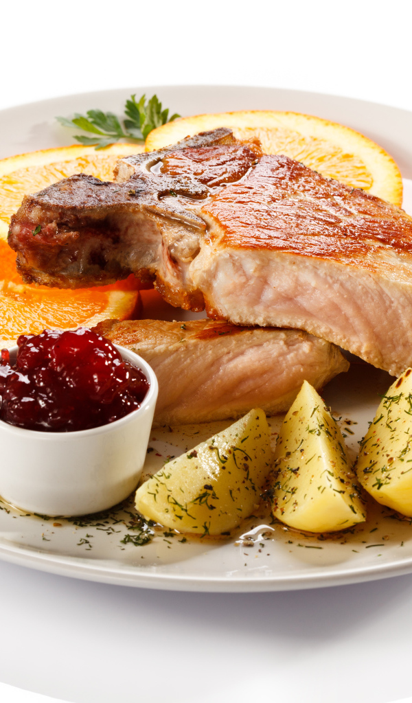 Картофель с мясом и кусочками апельсина на тарелке