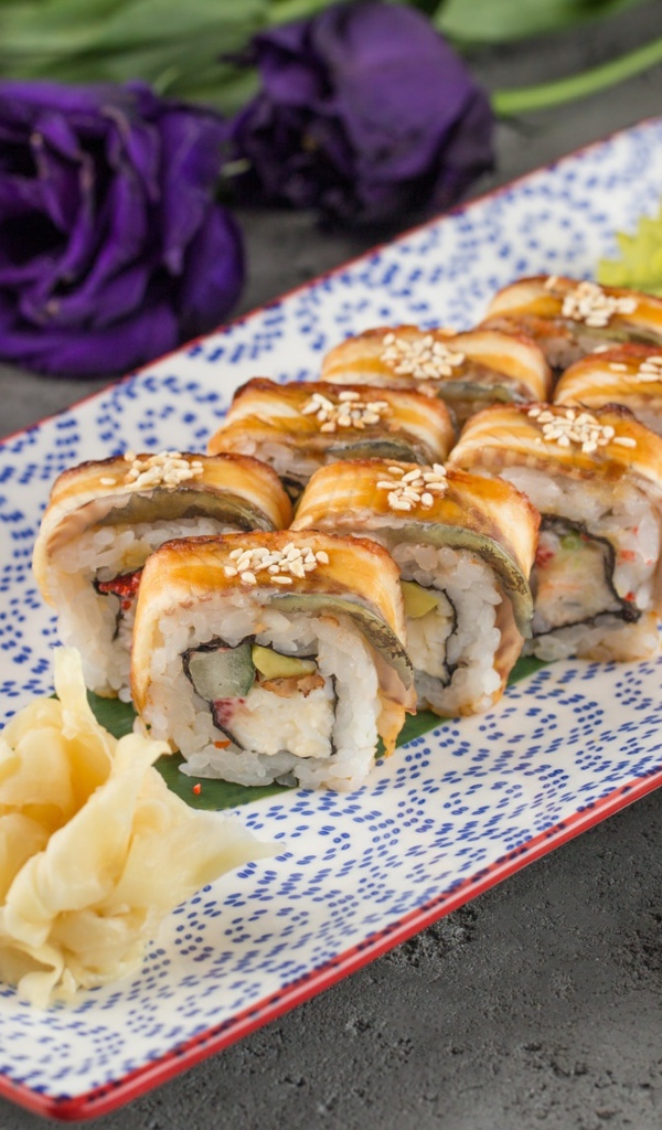 Роллы с авокадо и соевым соусом на столе с цветами 