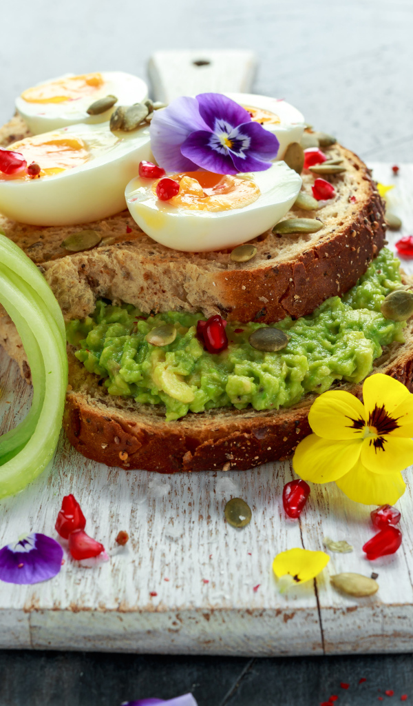 Сендвич с яйцом и цветами на доске