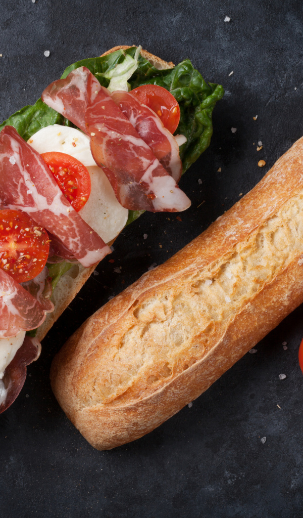 Бутерброд с ветчиной, помидорами, яйцом и листьями салата