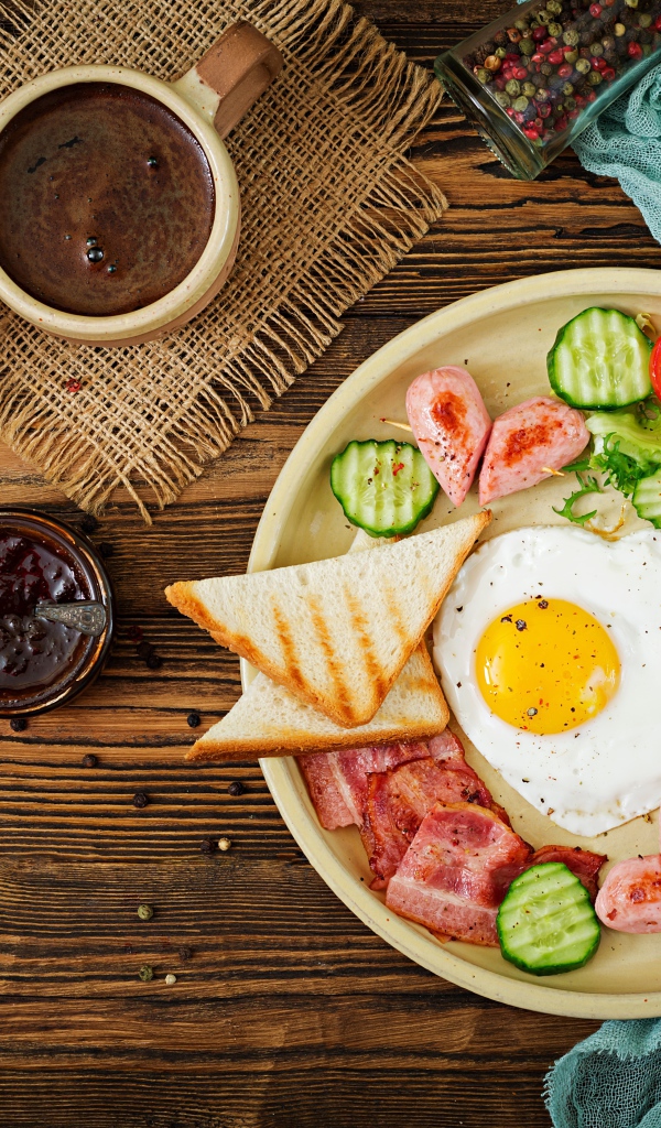 Яичница с беконом и овощами на столе с кофе к завтраку