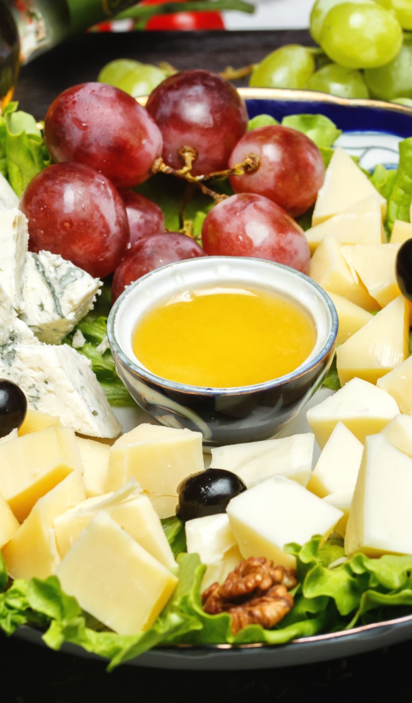 Нарезанный сыр на тарелке в виноградом 