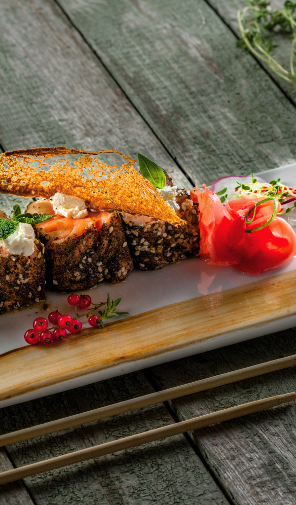 Суши на тарелке на деревянном столе с соусом