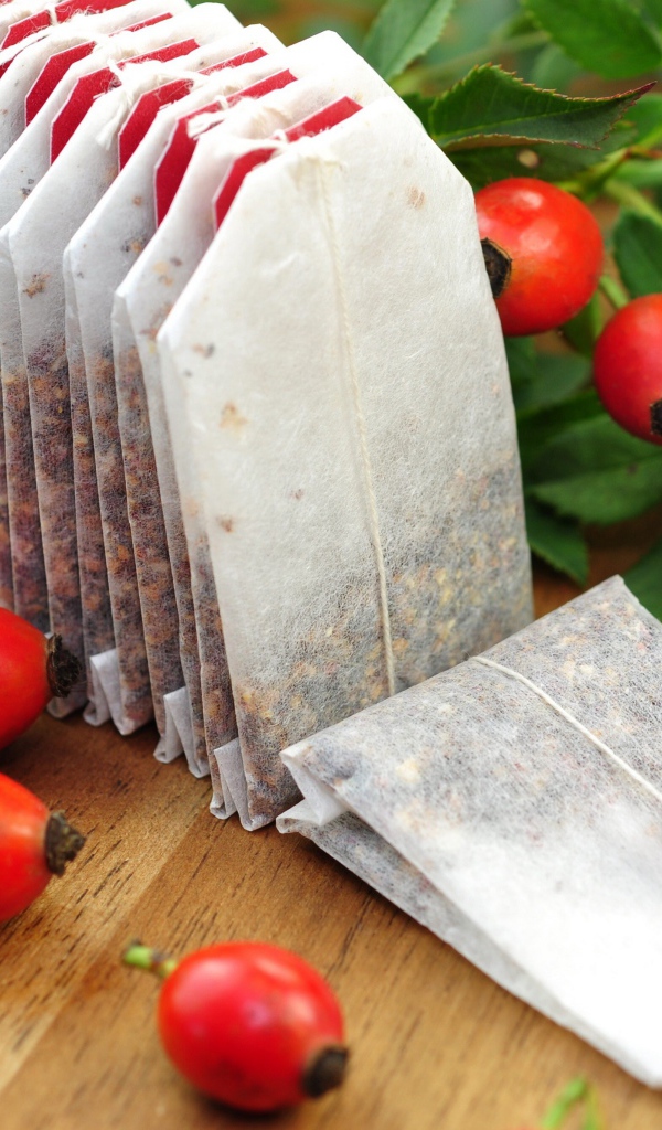 Чай в пакетиках на столе с ягодами шиповника 