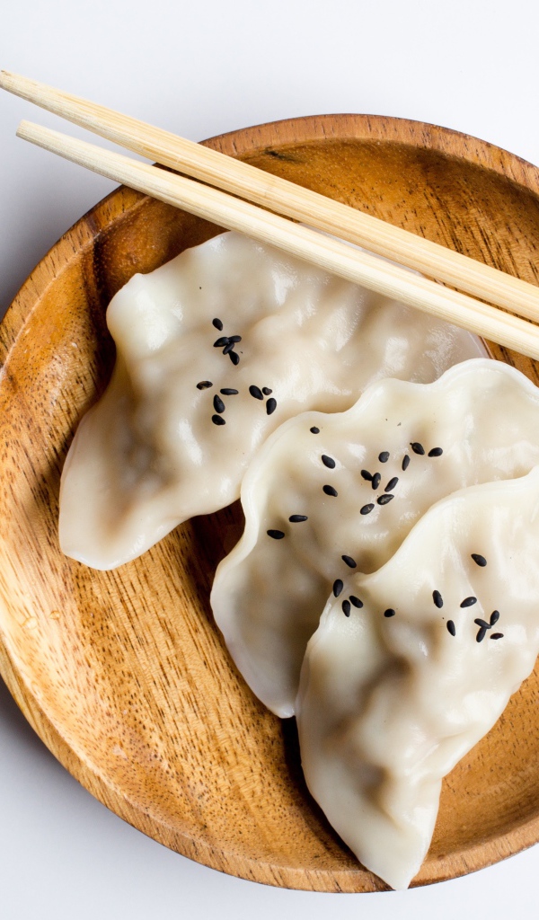 Три вареника на деревянной тарелке с палочками