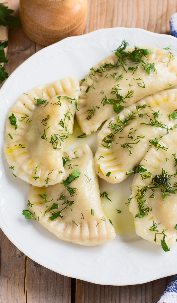 Вареники с зеленью на белой тарелке 
