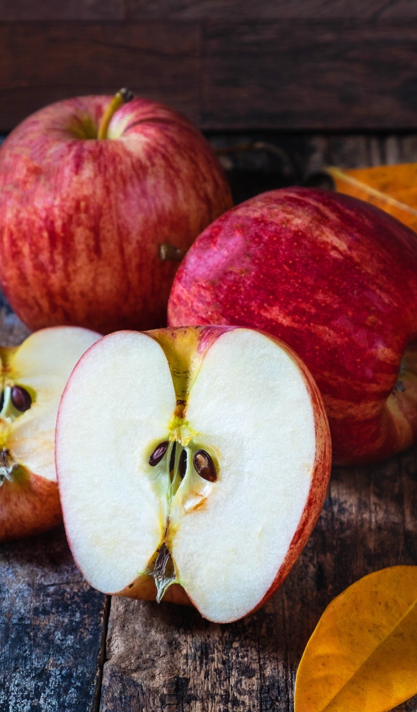 Красивые красные яблоки на столе с желтыми листьями