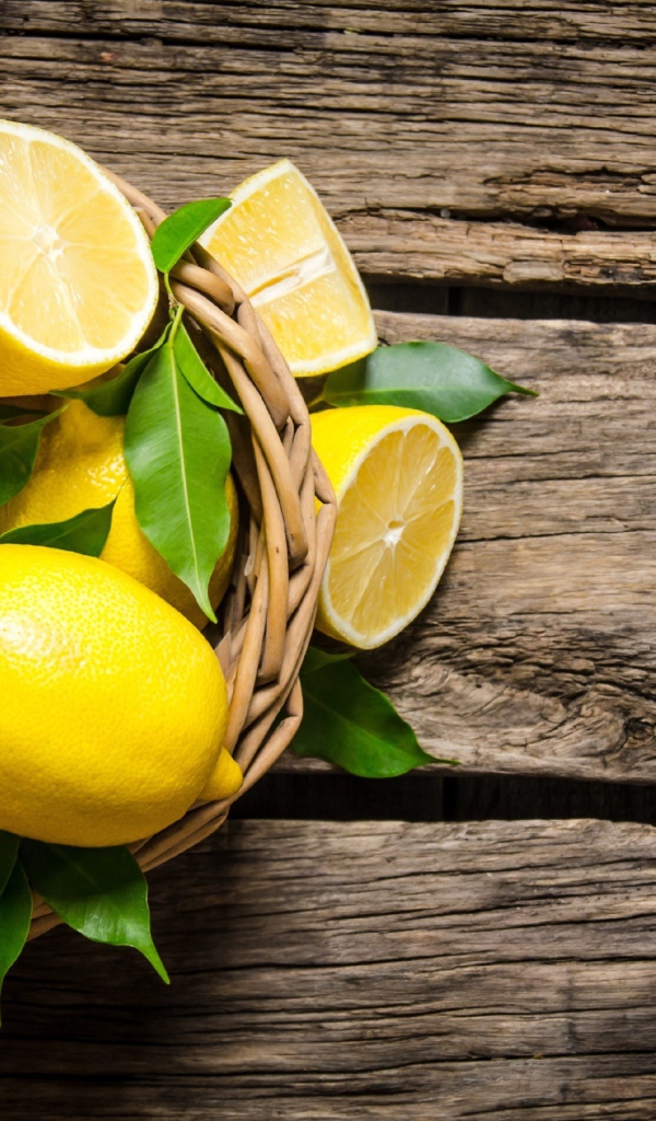 Красивые желтые лимоны в корзине на деревянном столе