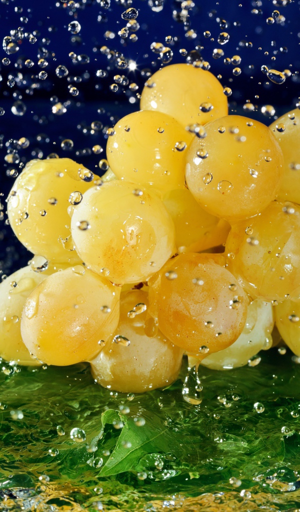 Гроздь белого винограда в брызгах воды