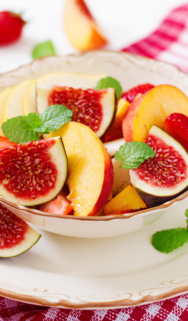 Свежие кусочки инжира и яблока в тарелке на столе