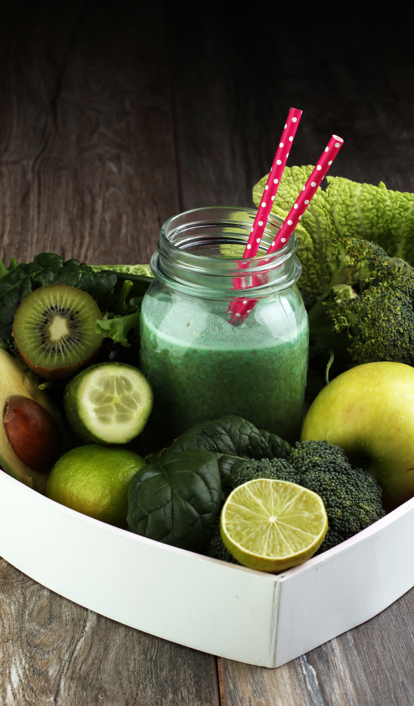 Зеленые овощи и фрукты в тарелке с баночкой смузи