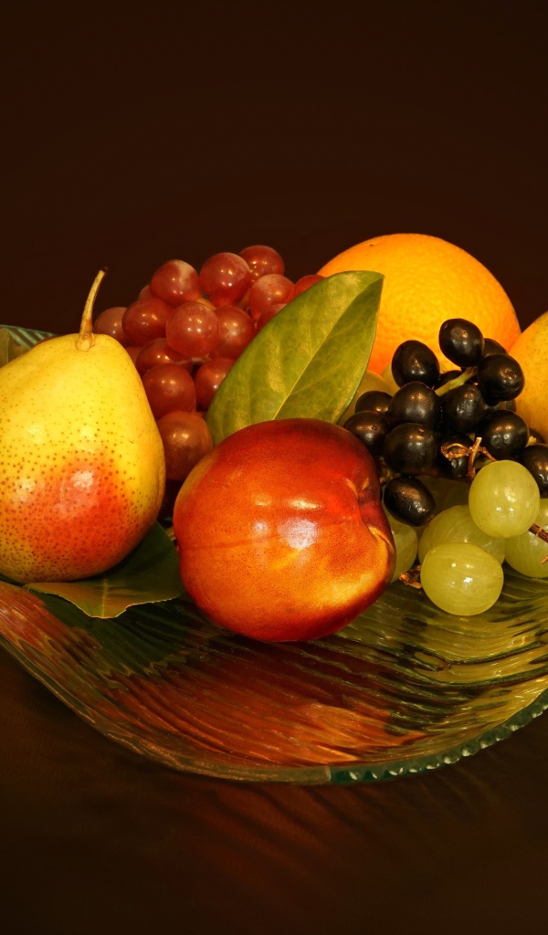 Груши, виноград, нектарин в красивой стеклянной вазе