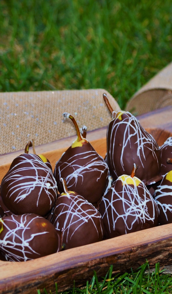 Груши в шоколадной глазури стоят на зеленой траве
