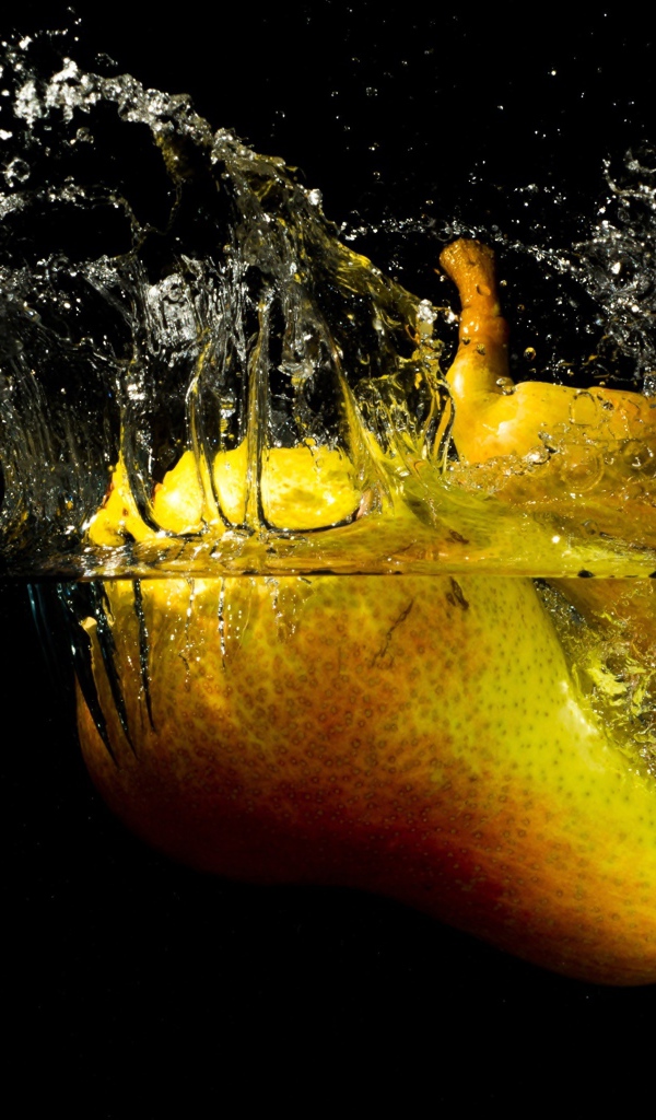 Груши в воде с брызгами на черном фоне