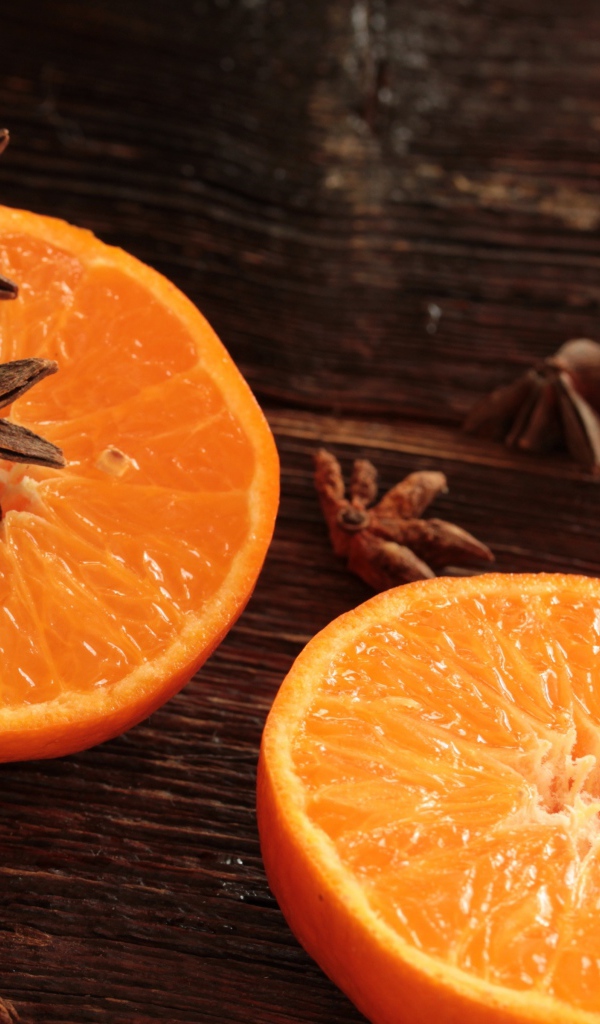 Две половины апельсина на деревянном столе с бадьяном