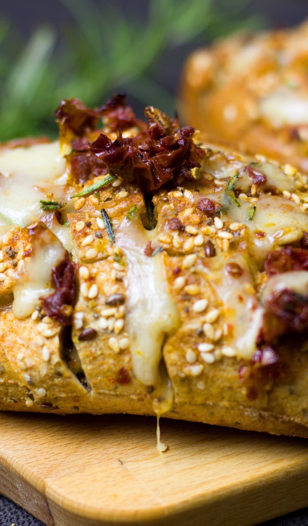 Булочка с кунжутом и сыром на разделочной доске 