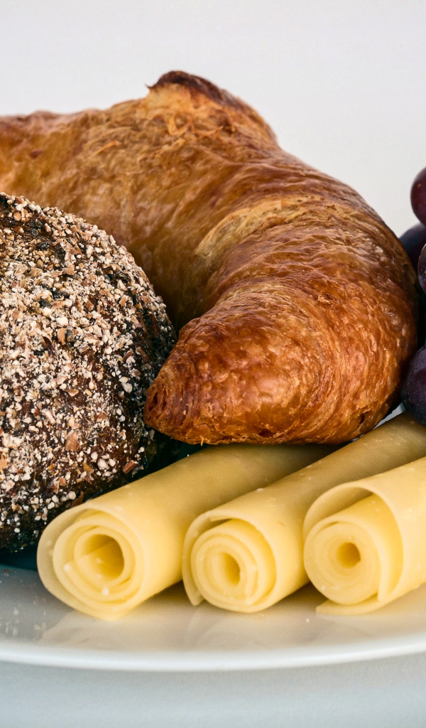 Свежая выпечка с сыром и розовым виноградом на белой тарелке 