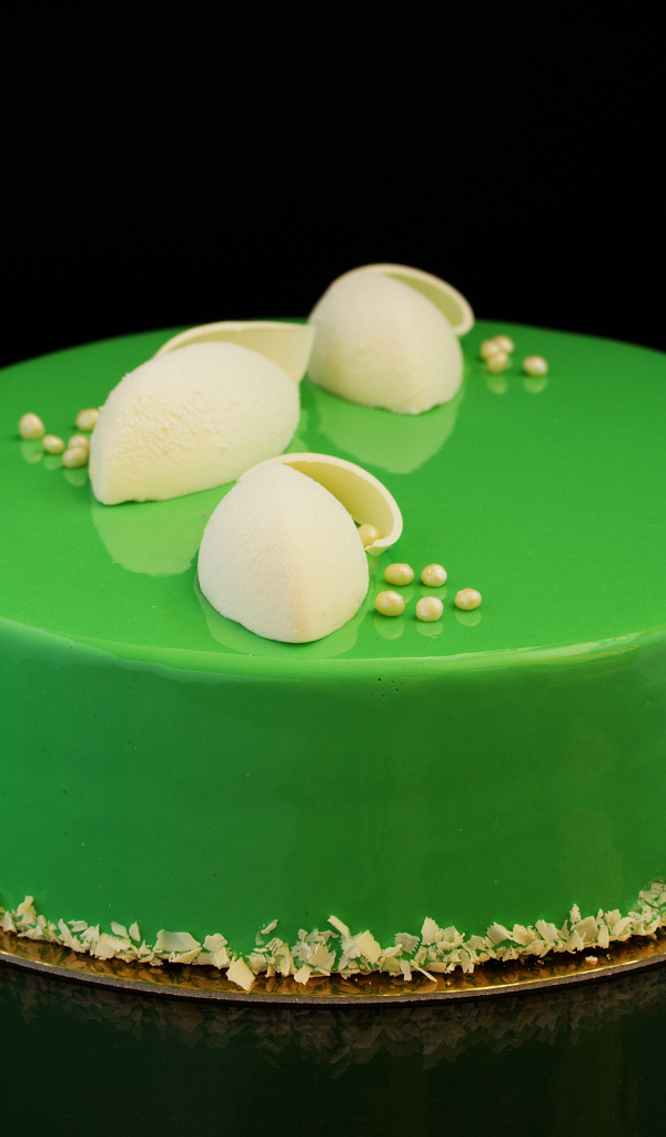 Зеленый глянцевый торт отражается в черной поверхности 