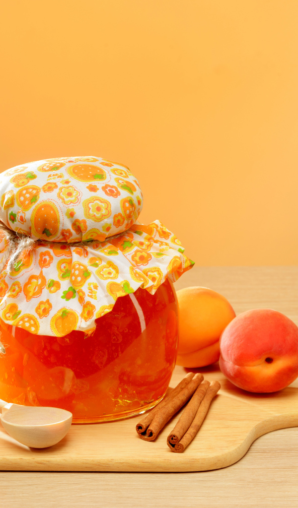 Банка абрикосового джема на столе с фруктами