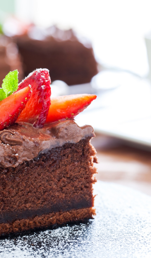 Кусок пирога с шоколадным кремом и кусочками спелой клубники 