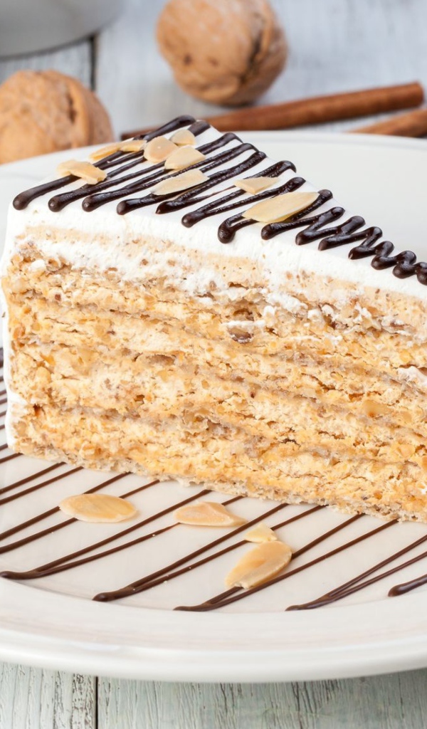 Кусок торта с орехами и шоколадом на белой тарелке