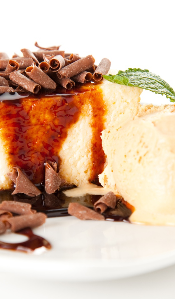 Кусок чизкейка с шоколадом и шариком мороженого на белой тарелке 