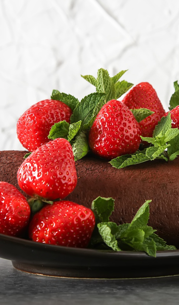 Кусок шоколадного торта со свежей клубникой на тарелке