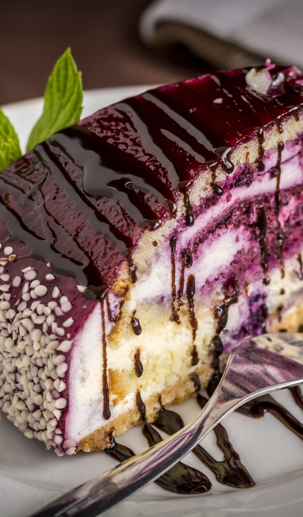 Кусок черничного пирога с джемом на белой тарелке с вилкой