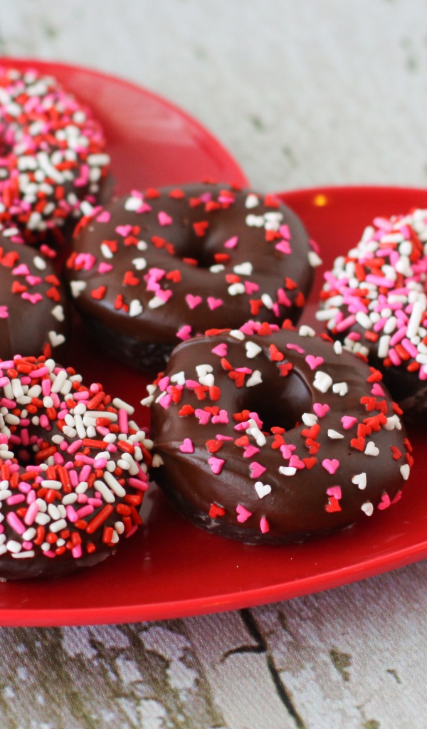 Аппетитные пончики на красной тарелке в форме сердца