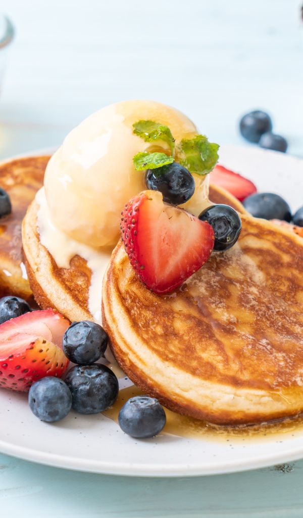 Аппетитные оладьи с мороженым, медом и ягодами клубники и черники
