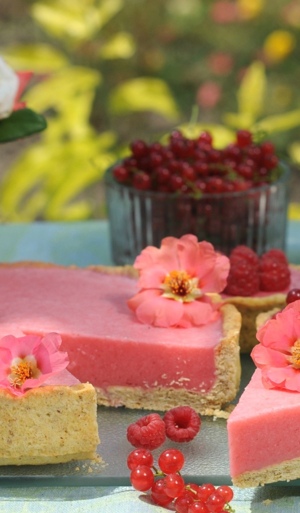 Аппетитный пирог с ягодами малины и красной смородины на столе с цветами