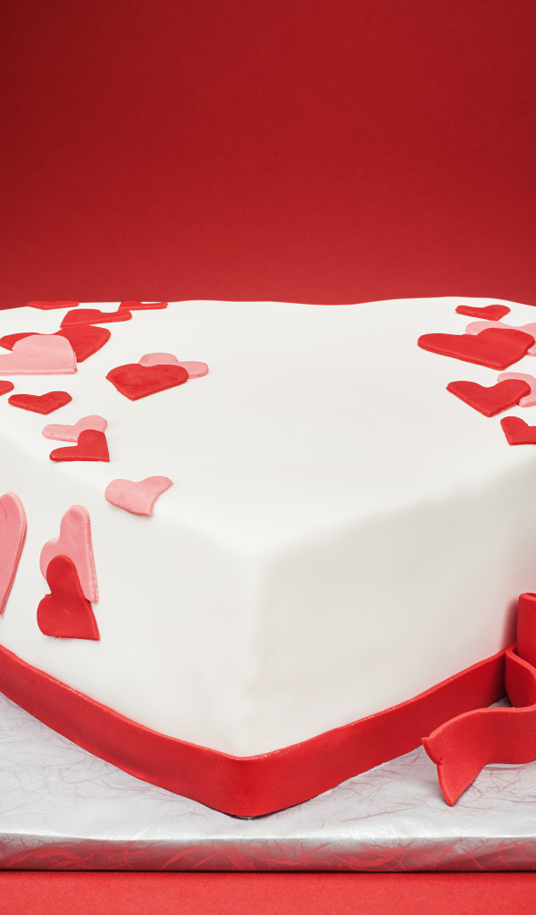 Красивый торт в форме сердца на красном фоне