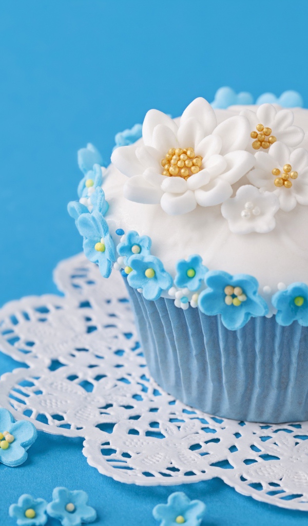 Красивый кекс украшен сахарными цветами на голубом фоне