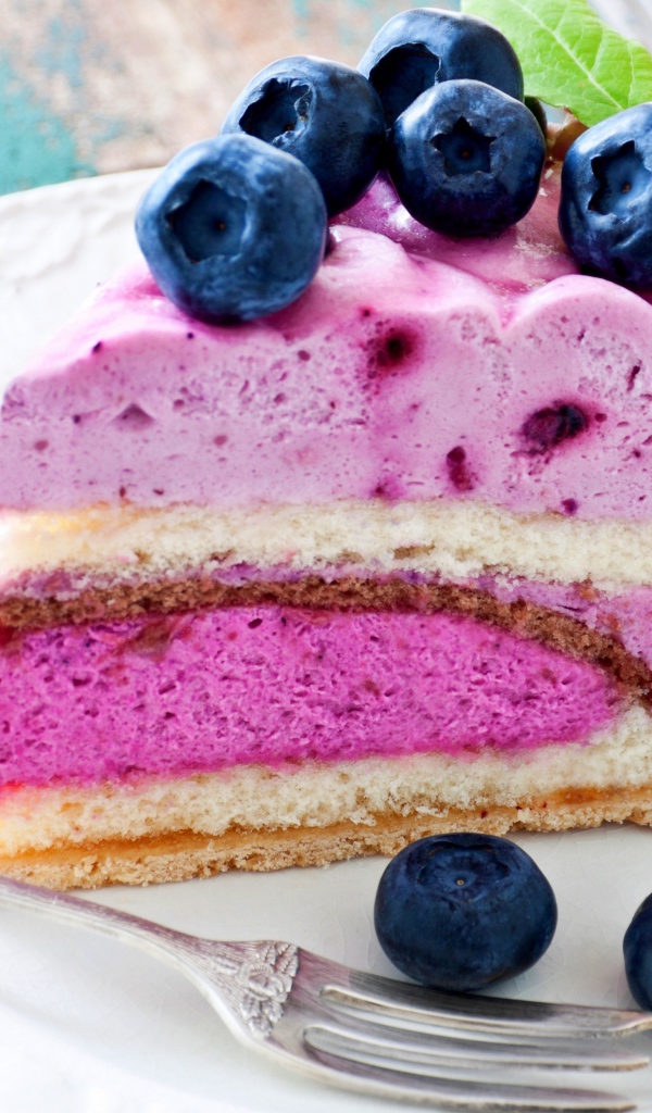 Торт с черничным муссом и свежими ягодами черники на белой тарелке 