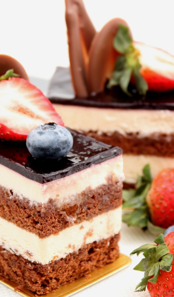 Пирожные с шоколадом, кремом и ягодами клубники и черники