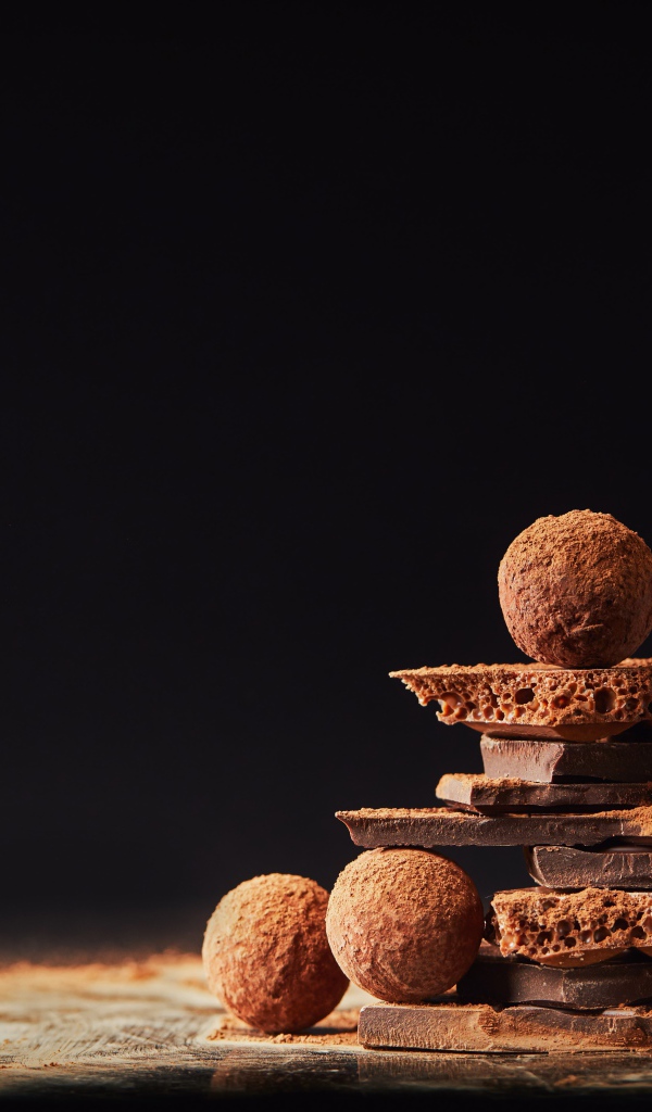 Шоколадные шарики и кусочки шоколада на черном фоне