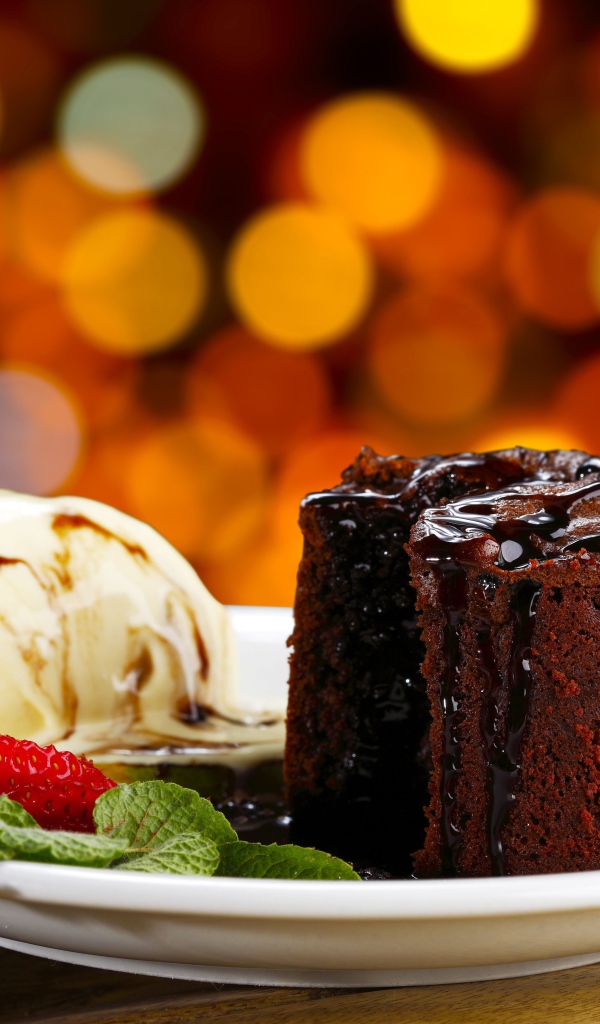 Шоколадное пирожное с мороженым и клубникой на тарелке