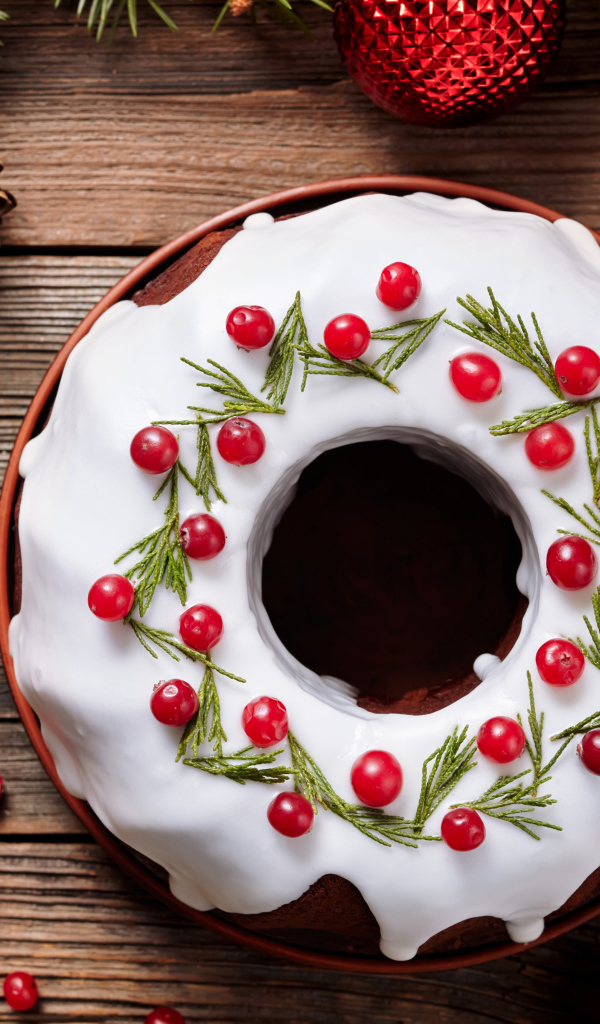 Рождественский пирог с ягодами клюквы на деревянном столе с еловыми ветками