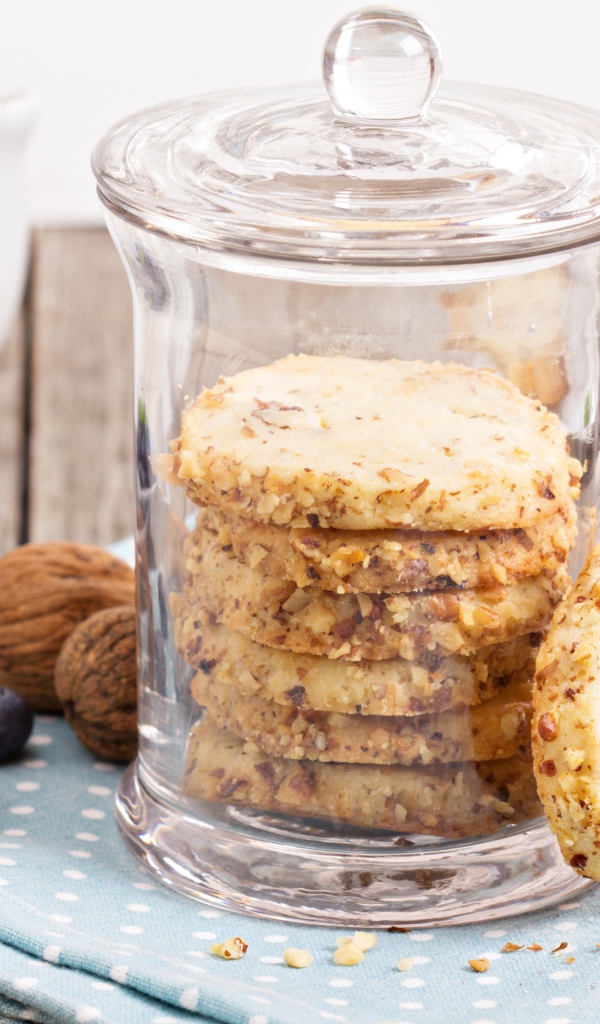 Печенье в стеклянной банке на столе с орехами и черникой