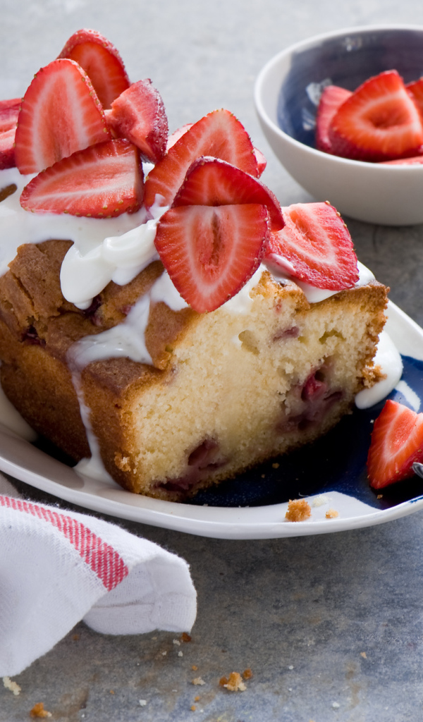 Кекс с кремом на тарелке со свежей клубникой 