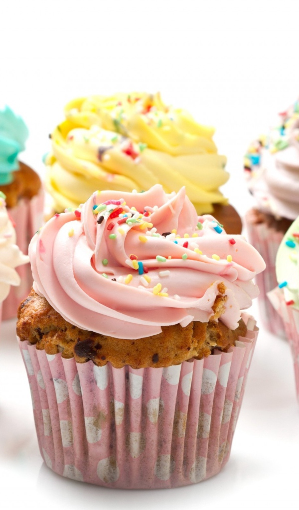 Кексы с разноцветным кремом на белом фоне