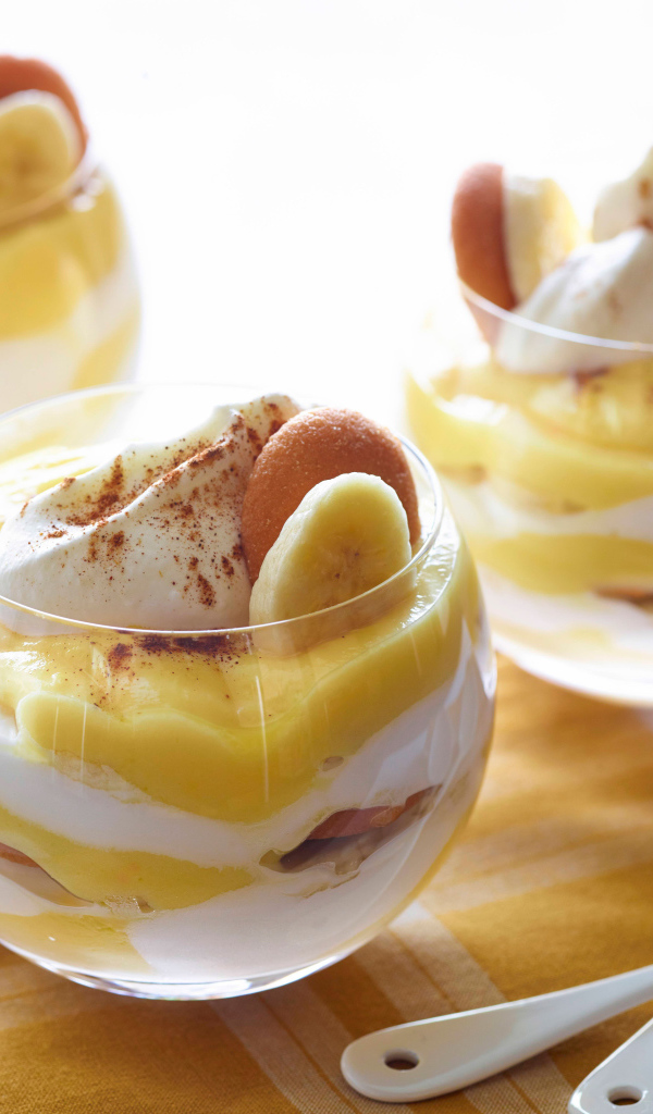 Десерт с бананами и печеньем в стаканах на столе 