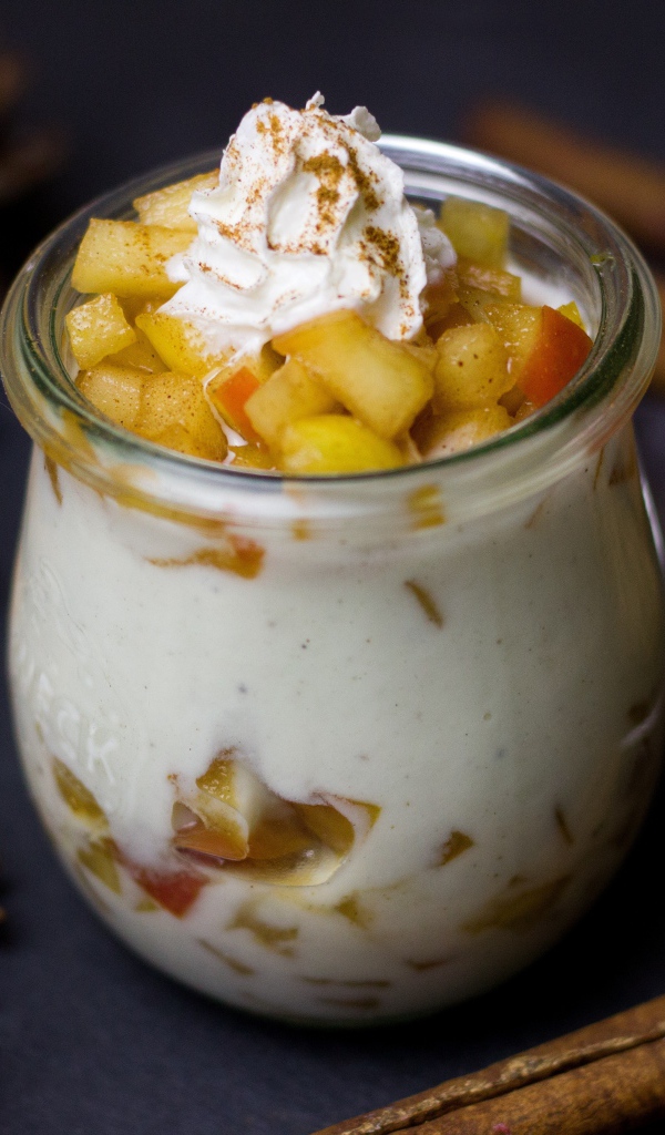 Десерт из йогурта с фруктами на столе с пряностями