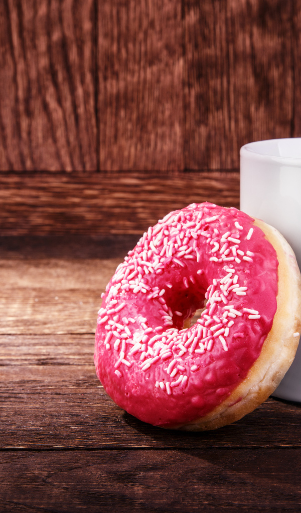 Пончик с белой кружкой на деревянном столе