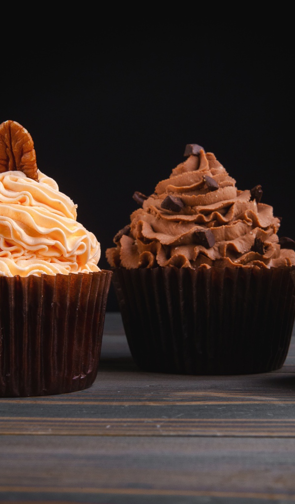 Четыре аппетитных капкейка с кремом на черном фоне