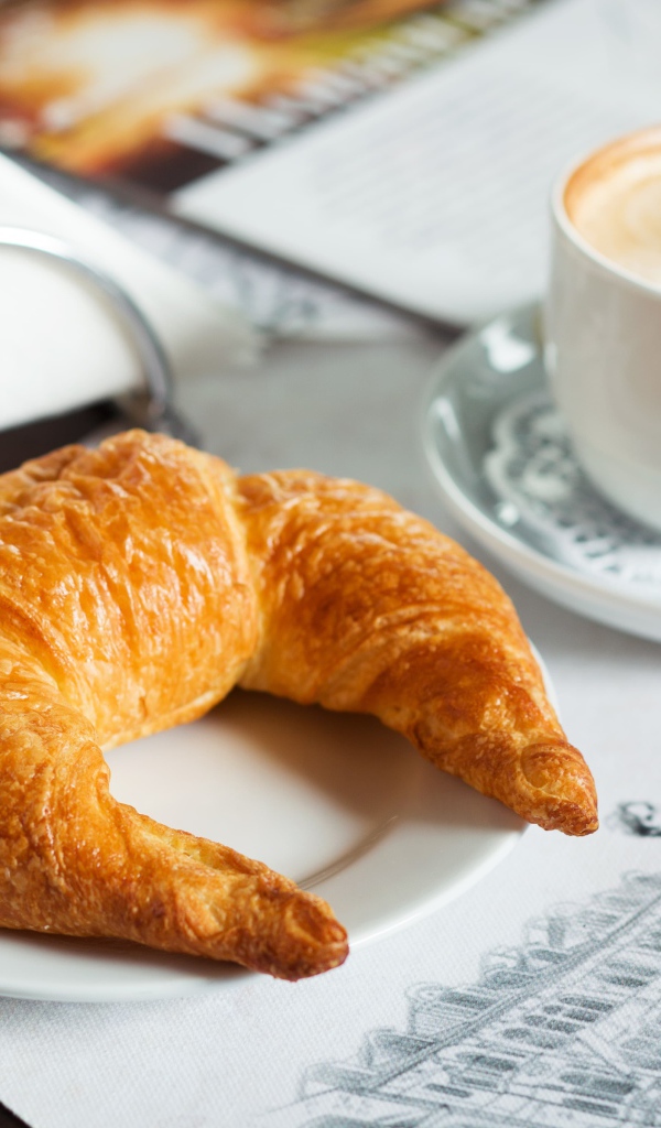 Свежий круассан и чашка кофе на завтрак 