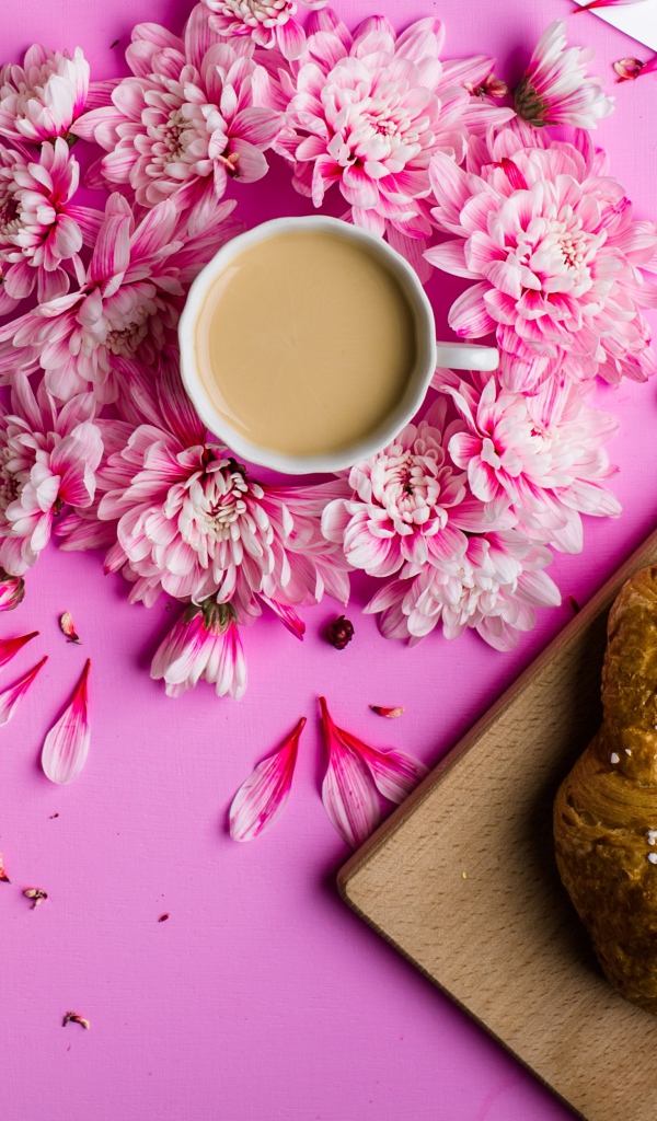 Свежие круассаны на столе с чашкой какао и цветами хризантемы