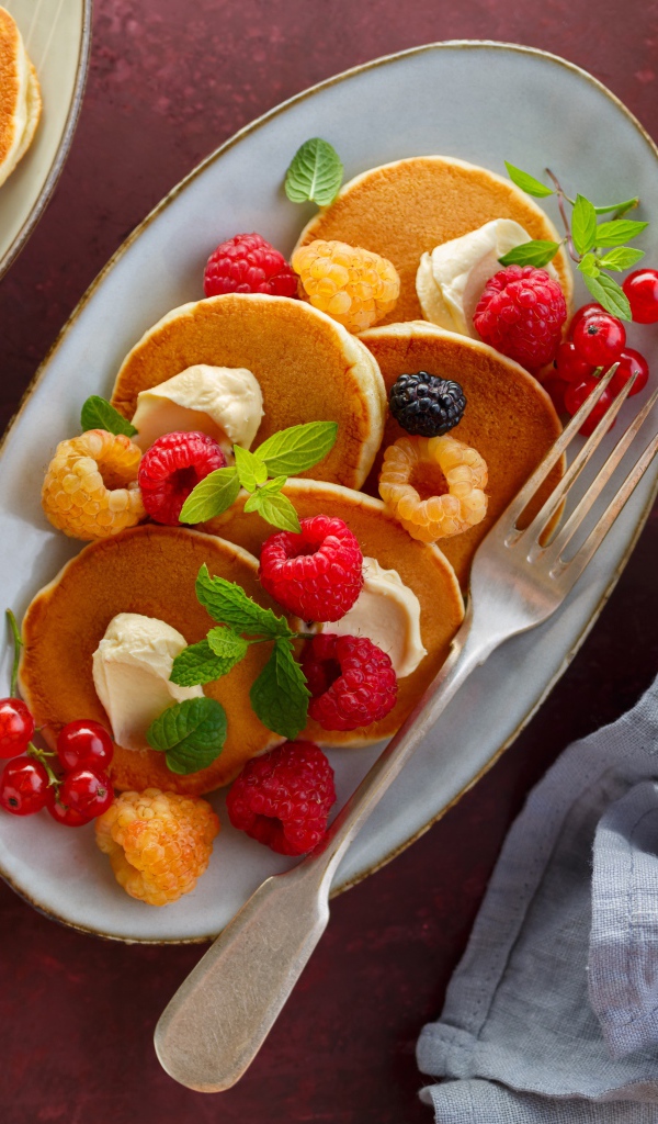 Оладьи на столе с ягодами малины и мороженым